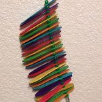 A colorful bird toy hanging on a wall.